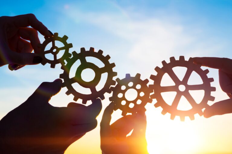 Meedere tandwielen die in elkaar draaien voor een blauwe lucht