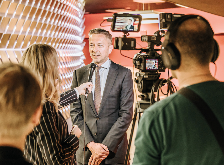 Man in pak wordt geinterviewd met microfoon en camera