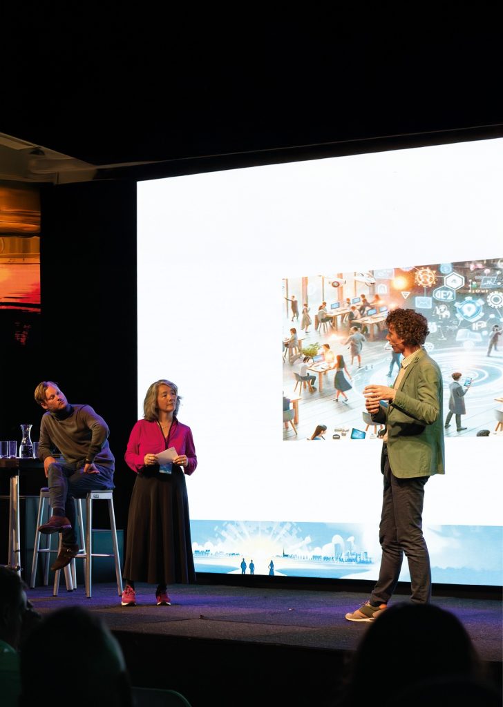 Personen op podium voor een groot scherm