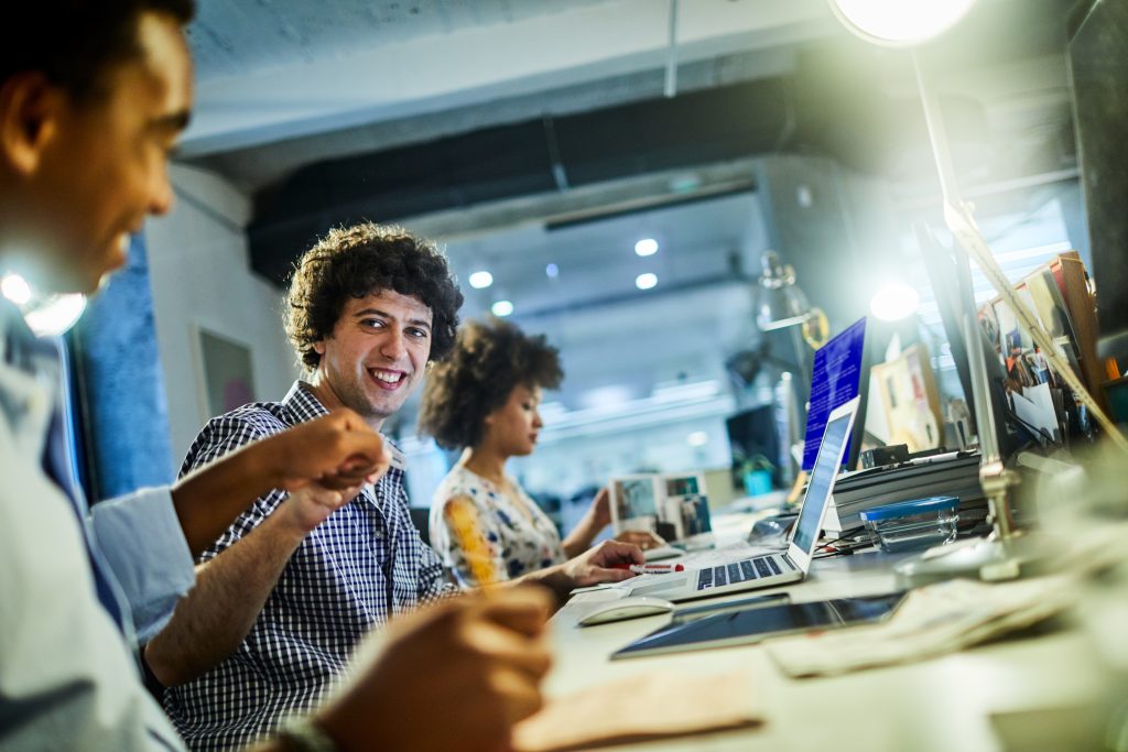 Drie mensen werken samen aan een bureau in een open kantoorruimte