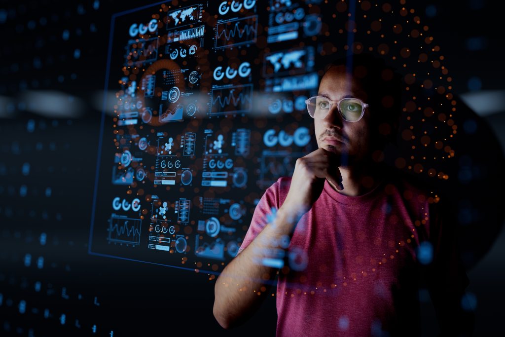 Man met rood shirt kijkt naar technisch dashboard in donkere omgeving