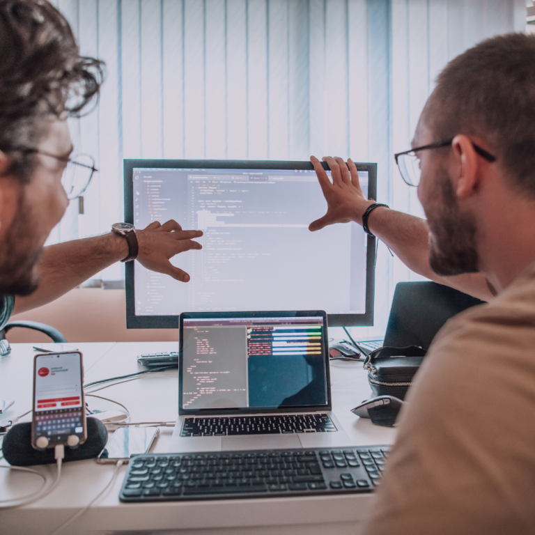 Twee mannen in gesprek van achter gezien, wijzen naar een scherm