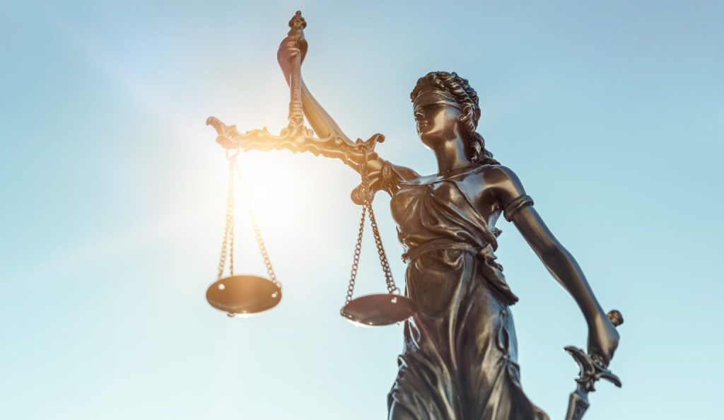 Lady Justice with scales and sword in sunlight, symbolizing justice, administration of justice and legislation.