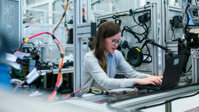 Technische vrouw werkt geconcentreerd aan bedrading en apparatuur in een lab.