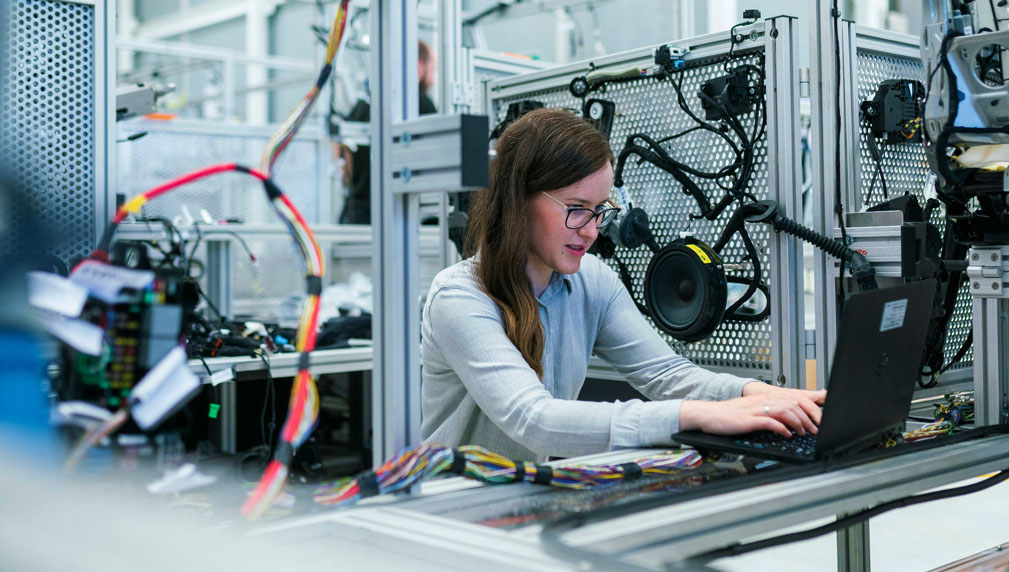 Technische vrouw werkt geconcentreerd aan bedrading en apparatuur in een lab.