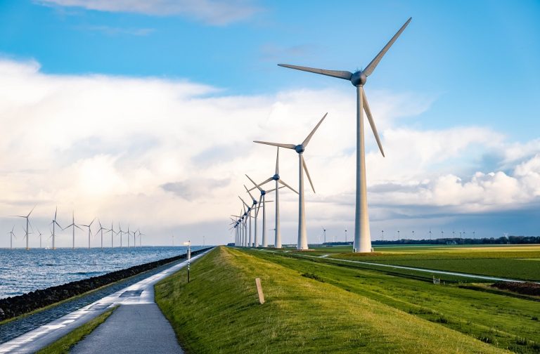 Rij windmolens op een groene dijk met groen gras en blauwe lucht