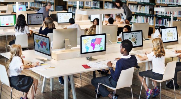 Open kantoorruimte met kinderen achter computers, werkend aan data of geografische software.
