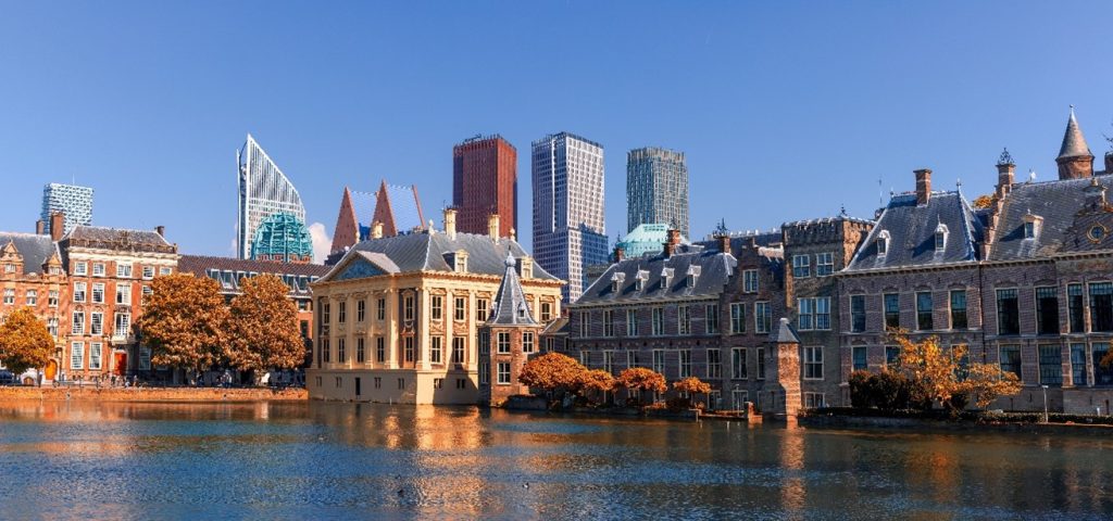 Binnenhof den haag Skyline van een stad met moderne gebouwen en een klassiek pand aan het water.