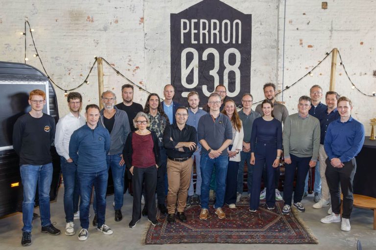 Groepsfoto van Learning Community AMELIA voor een muur met daarop het logo van Perron 038