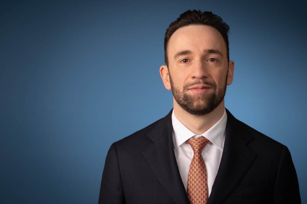 Staatssecretaris Silvio Erkens in pak, kijkt lachend in de camera.