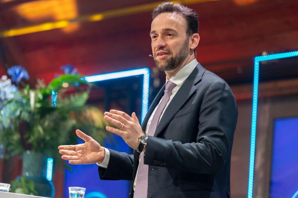 Staatssecretaris van het Ministerie van Landbouw, Visserij, Voedselzekerheid en Natuur Silvio Erkens staat met open handen als uitnodigend gebaar op het podium bij het Nederlands AI Congres