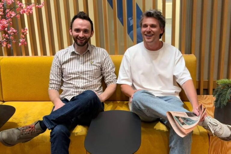 Wout Eggink and Patrick Rietschoten, the owners of Twin AI, are sitting together on a couch in an office space with wood paneling.